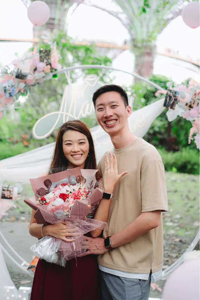 A romantic couple posing with a pink and red floral bouquet.